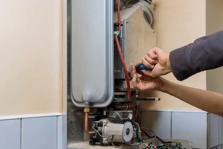 riparazione impianto acqua calda con cacciavite da tecnico caldaie in Lombardia