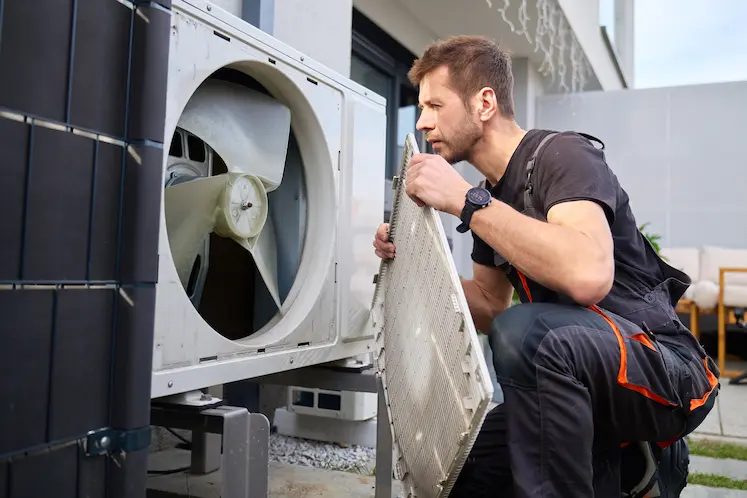 tecnico certificato F-Gas ispeziona unita esterna condizionatore in condominio lombardo
