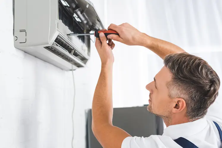 tecnico ripara l'unita di condizionamento con cacciavite in appartamento marchigiano