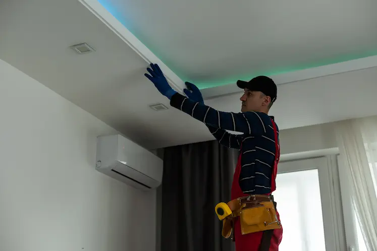 Tecnico elettricista che lavora sul soffitto con gli attrezzi a Como