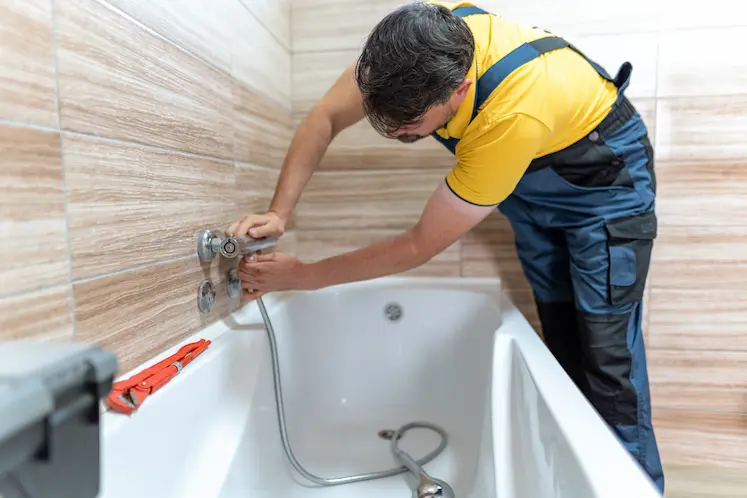 idraulico urgente lavora sul rubinetto del bagno in condominio lombardo