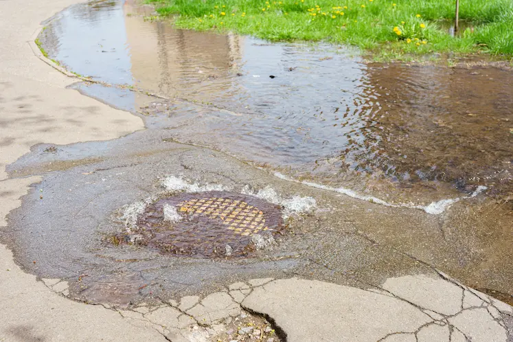 acqua che fuoriesce dal tombino fognario rotto su strada urbana in Abruzzo